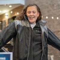 Event attendee smiling and looking down with arms out